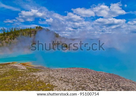 Beautiful cerulean geyser against cloudy summer sky