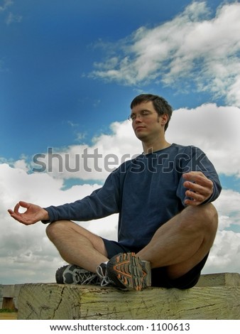 Man meditates outside on a bench