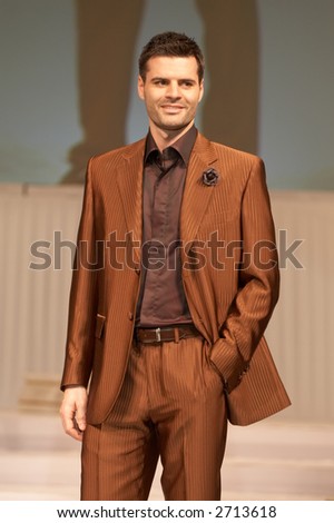Young man in classic, elegant brown suit with one hand in pocket