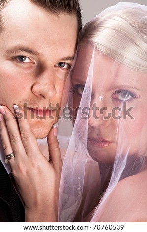 Young bride in veil holding the chin of the groom