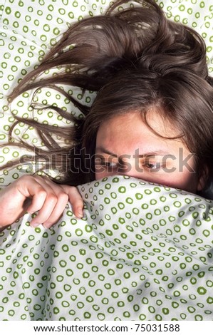 Young scared girl hiding under blanket