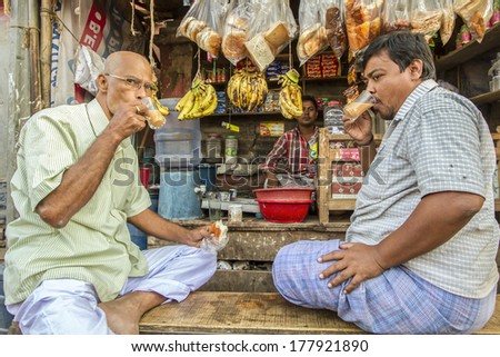 DHAKA, BANGLADESH - NOVEMBER 23, 2013: Two men drink tea at a stall in Old Dhaka.  Tea, heavily mixed with milk and sugar, is very popular in Bangladesh.