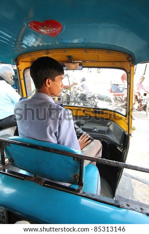 JAIPUR, INDIA - SEPTEMBER 23:  An unidentified young driver of an auto rickshaw waits at a traffic light in Jaipur, Rajasthan, India on September 23, 2011.  Rickshaws provide economical transportation throughout India.
