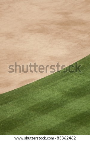Vertical photo of infield dirt and outfield grass background at a baseball stadium.