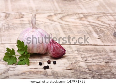 Garlic clove, pepper and parsley leaves on wooden background