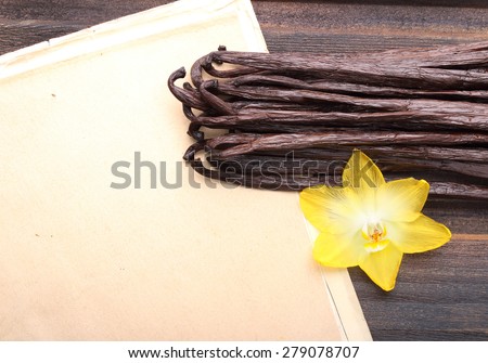 Vanilla pods and orchid flower on wooden background