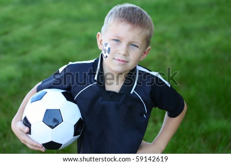 A young boy with painted face and soccer ball.
