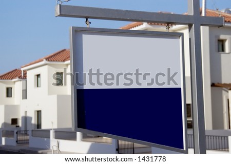 blank for sale board with new development of white villas in background