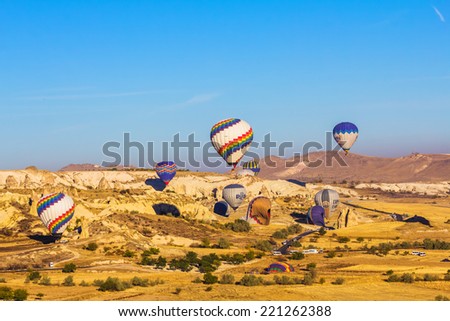 GOREME - OCTOBER 10: Colorful hot air balloons flying  over rock landscape and landing on valleys in Cappadocia on October 10, 2013 in Goreme, Turkey.