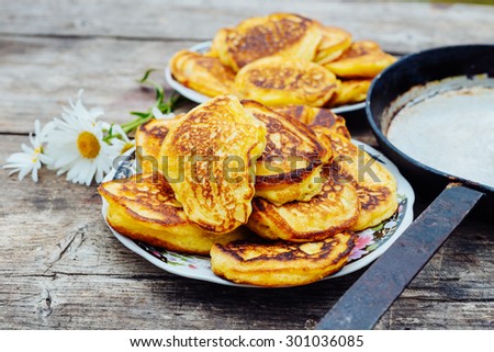 Pancakes on a plate next to the frying pan on a wooden table, DOF