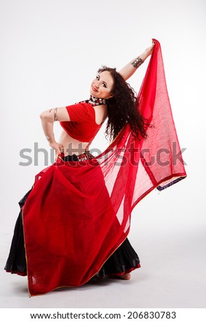 tribal dancer in black  skirt dancing with red fling shawl in studio on gray background