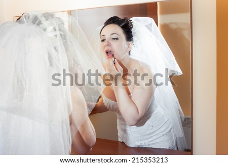 beautiful brunette bride in wedding dress look at the mirror