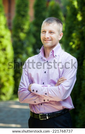 handsome man in pink shirt look at the camera with green trees on background