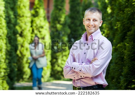 handsome man in pink shirt look at the camera with green trees on background