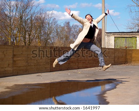 Lady in grey coat jumping over a water puddle