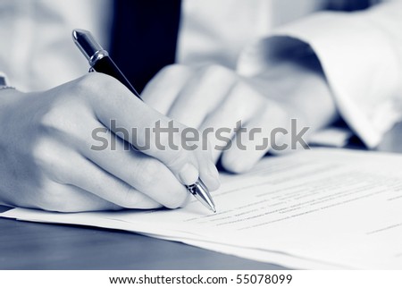 person\'s hand signing an important document