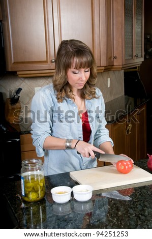 Attractive young woman slices tomato