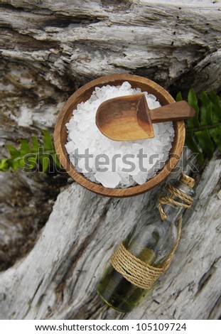 sea salt in bowl and massage oil with fern on old wood texture