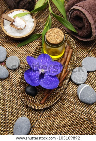 Spa setting with roller towels and salt in bowl and bamboo plant , massage oil ,orchid