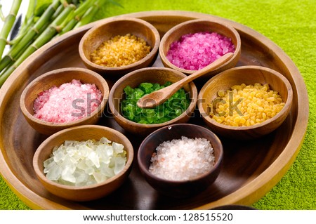 color sea salt in wooden bowl with bamboo grove ,massage oil on green towel