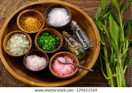 color sea salt in wooden bowl with bamboo grove ,massage oil on mat