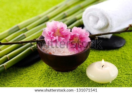 Sea salt in bowl and bamboo grove, towel ,candle ,cherry flower on green soft towel