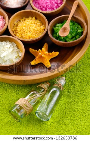 color sea salt, starfish in wooden bowl with massage oil on green towel