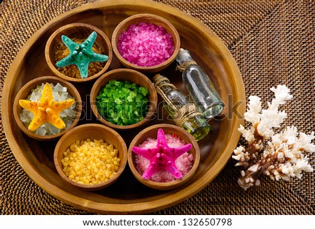 color sea salt with massage oil in wooden bowl with seashell , coralon mat