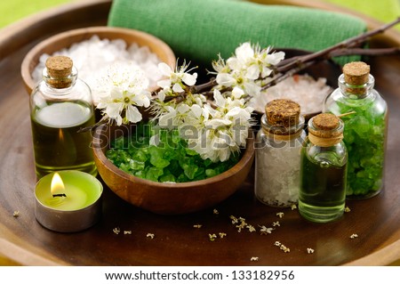 color sea salt in wooden bowl with salt in glass , cherry, candle, massage oil