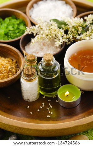 wooden bowl of color sea salt with ,candle ,massage oil on green towel