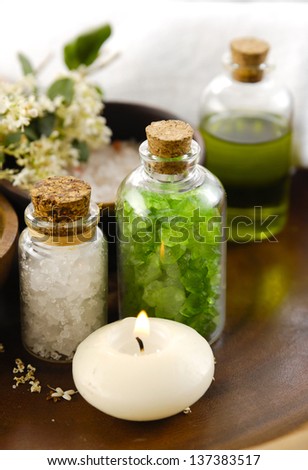 sea salt in wooden bowl with salt in glass , candle, massage oil