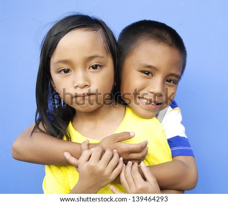 Loving brother and little sister hugging isolated over blue