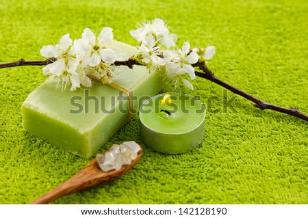 branch of white cherries flowers blossom with candle, soap ,salt in spoon on green soft towel