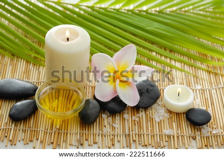Spa setting with candle ,green palm, frangipani on mat