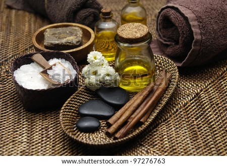 Towel with massage oil and stone in bowl and with gerbera on burlap texture