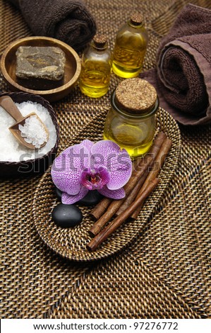 herbal salt in bowl and with orchid, stones and massage oil towel on burlap texture