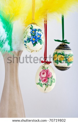 Easter table decorations, hand-painted eggs hanging on a vase with feathers
