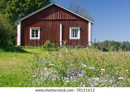 Old wooden red fisherman\'s cottage with wild pansies in the foreground