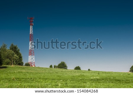 Communications tower at the blue sky and green meadow