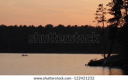 The silhouette of canoers in Algonquin Provincial Park at  dusk.