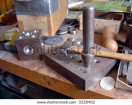 A metal work work shop bench with a hammer siiting on it.