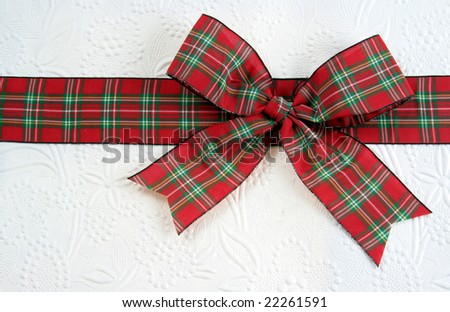 A plaid christmas bow on decorative white paper.