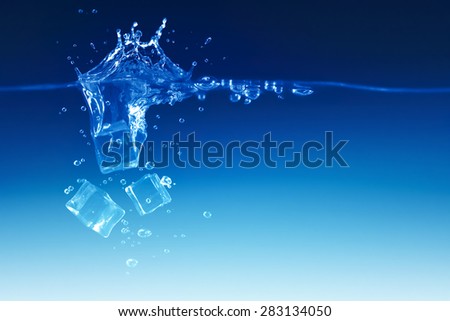 falling ice cubes to the water on blue background