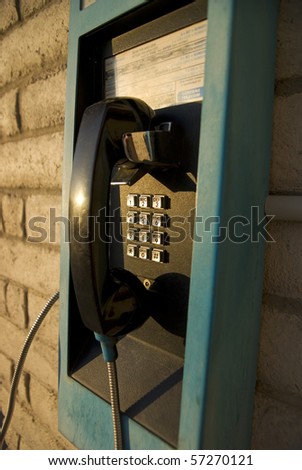 blue and black pay phone on white brick wall