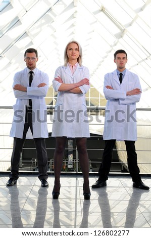 Portrait of a female doctor with two of her co-workers against modern hospital building