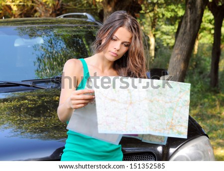 Young woman stand near the car and look on map