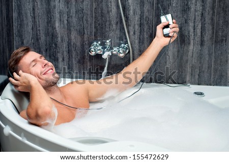 young man taking a bath, listening to music from the player