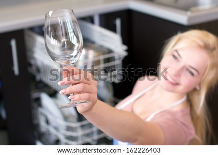 Kitchen Woman. Girl in the kitchen using dishwasher. view of young woman in kitchen doing housework. see clean the glass