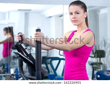 Fitness Woman. Happy woman training at the gym on cross trainer