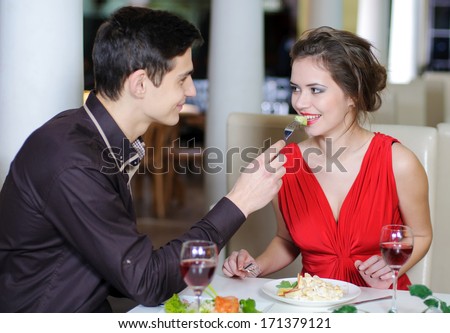Young happy couple romantic date drink glass of red wine at restaurant, celebrating valentine day